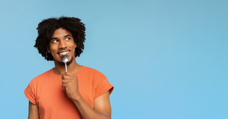 Curious african american man with spoon in his mouth