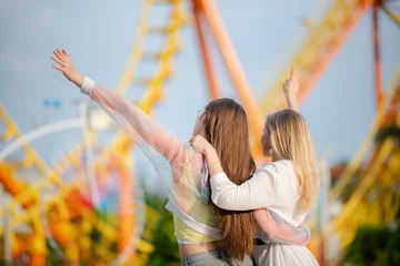 Foto auf Acrylglas young woman having fun and happy smiling together at amusement theme park outdoor © chokniti
