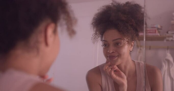 Young adult female smiling at her reflection in mirror