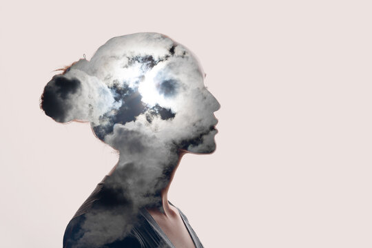 Psychology and woman mental health concept. Multiple exposure clouds and sun on female head silhouette.