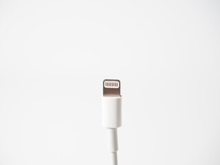 Close-up of a white lightning cable isolated on a white background. Cable for charging gadgets and transmitting information. Side view