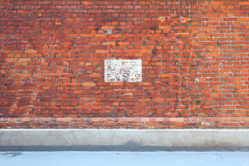 Empty, grunge brick wall at the urban concrete street. Industrial background. 