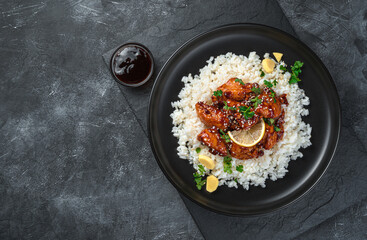 Japanese teriyaki chicken with rice on a dark background.