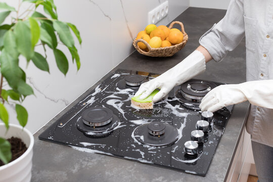 Woman In Rubber Gloves Cleaning Gas Stove Top With Sponge And Detergent. Clean House And Hygiene Concept