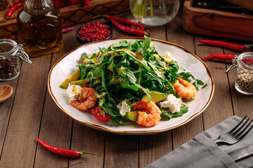 Gourmet shrimp salad with avocado and arugula on wooden background