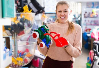 positive female consumer with children's plastic toys in the kids store