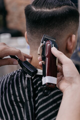 barber using hair clipper and comb to cut the hair in the barber shop.