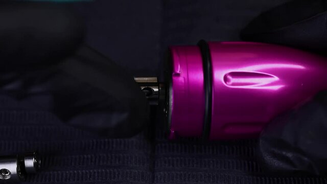 master of black gloves scrolls an eccentric on a tattoo machine