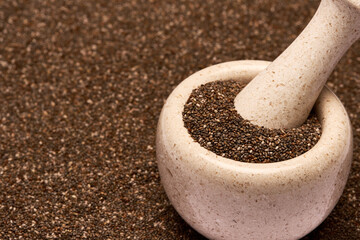 Wooden mortar full of organic natural chia seeds and pestel close-up