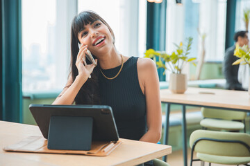 Obraz premium Cafe city lifestyle woman drinking coffee texting text message on smartphone or tablet sitting indoor in trendy urban cafe. business woman working with laptop on a wood table.