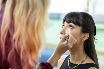 Make-up artist work on woman business model.Artist applying powder with a brush on model's cheeks, selective focus on model .