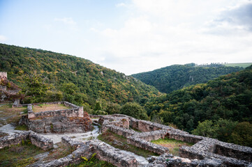 Fototapeta na wymiar Mauern einer Burgruine mit bewaldeten Bergen im Hintergrund in den ersten Herbstfarben