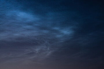 Fototapeta na wymiar Noctilucent clouds close up on a summer night. Glowing clouds in the night sky.