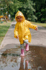 Girl in a yellow dress with an umbrella joyful spring runs through the puddles on a rainy day