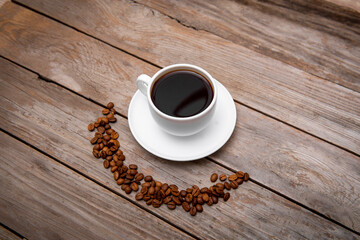 Top view of coffee beans in a shape of smile and coffee cup of espresso on wooden table