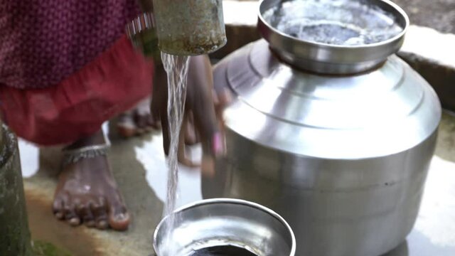 Filling metal container with drinking water from hand pump, India