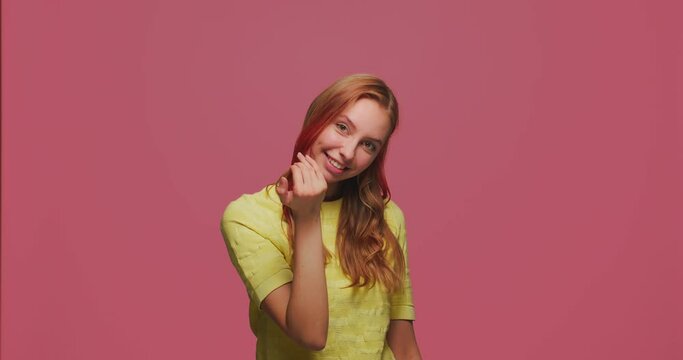 Come here gesture. Smiling young girl making beckoning gesture with palm, inviting to approach, looking playful flirting