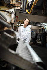 Fototapeta na wymiar Woman in robe working at factory with machines