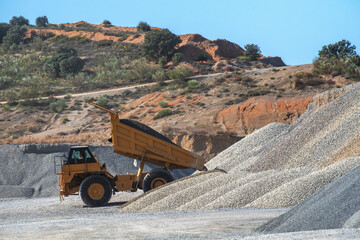 Large dump truck with the tipper raised unloading sand in a quarry.