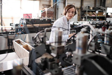 Female executive working at factory with machines