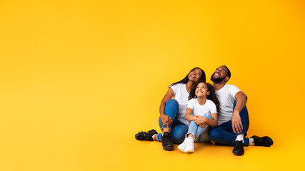 Smiling black family looking up at free copy space