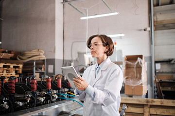 Female executive working with tablet, checking factory machines