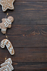 Christmas background with gingerbread cookies and warm garland on a wooden brown texture