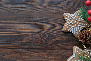 Christmas background with gingerbread cookies with a spruce branches and pine cones and wooden brown texture