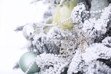 Christmas holiday background. Silver and color bauble hanging from a decorated on tree with bokeh and snow, copy space.