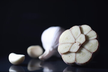 Fresh garlic clove on black background. Garlic is rich in vitamins, useful spring, good spices. Garlic sliced on a dark background. Raw sliced garlic.
