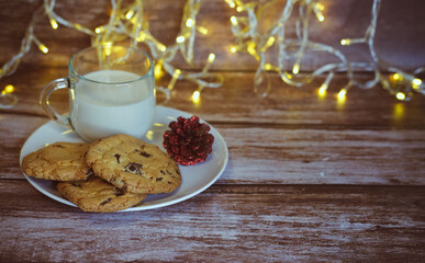 Milk with Christmas cookies for santa claus on a wooden table, selective focus