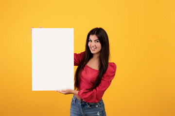 Obraz na płótnie Canvas Place for your ad. Happy armenian woman holding blank placard with copy space for advertisement, text or design