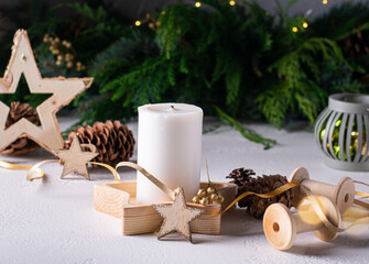 White advent candle on wooden box with christmas lights, cones, wooden star. Copy space