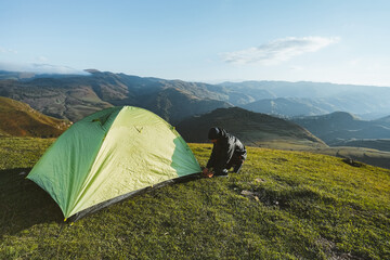 Male hiker is setting up a bright green tent in the mountains. Concept of tourism, hiking - 470428140