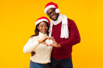 Black Couple In Santa Hats Showing Heart Gesture, Yellow Background
