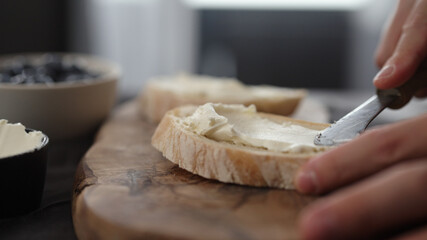 man hand spreading cream cheese on slice of ciabatta