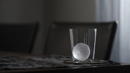 clear ice ball in tumbler glass on table