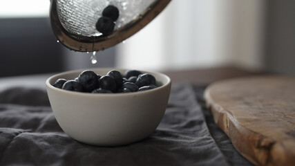 pour washed blueberries into white bowl on table