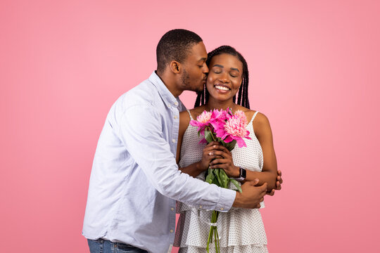 Happy black man making surprise for woman giving flowers