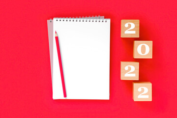 2022 arrange on red background. Notebook with white page for your write. Golden Numbers 2022. Balls, Fir, Pine, goal, New Year, New You and happy holiday concept. Christmas Celebration mock up