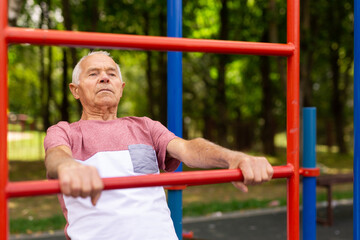 Obraz premium Mature man practice on the sports ground equipment in park