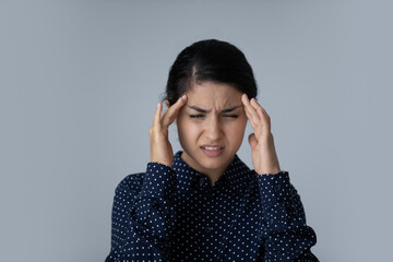 Head shot stressed young multiracial Indian ethnicity woman massaging temples, suffering from...