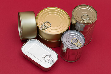 A Group of Stacked Tin Cans with Blank Edges on Red Background. Canned Food. Different Aluminum Cans for Safe and Long Term Storage of Food. Steel Sealed Food Storage Containers