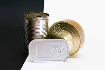 A Group of Stacked Tin Cans with Blank Edges on Split Black and White Background. Canned Food. Different Aluminum Cans for Safe and Long Term Storage of Food. Steel Sealed Food Storage Containers