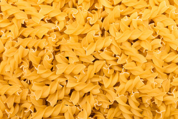 Uncooed Fusilli Pasta - Background. Texture of Bright Golden Dry Macaroni