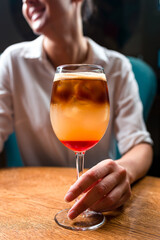 woman with a cocktail at the table, a cocktail with cold coffee and an aperol