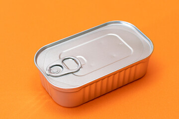 Unopened Tin Can with Blank Edge on Orange Background. Canned Food. Aluminum Can for Safe and Long Term Storage of Food. Steel Sealed Food Storage Container