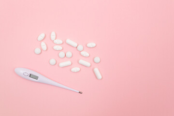 White Pills or Tablets with Electronic Thermometer on Pink Background. Pharmaceutical Industry and Medicinal Products