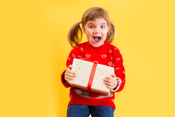 Happy child girl holds Christmas presents against yellow background. Merry Christmas! Copy space. birthday
