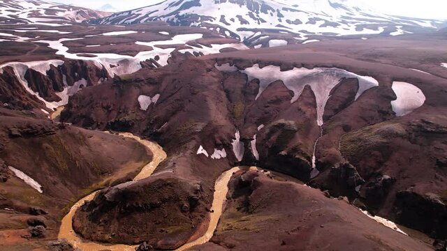 Aerial shot of Iceland highlands, snow covered mountains. Rivers below, shot pans up to reveal. Shot at Kerlingarfjöll. 